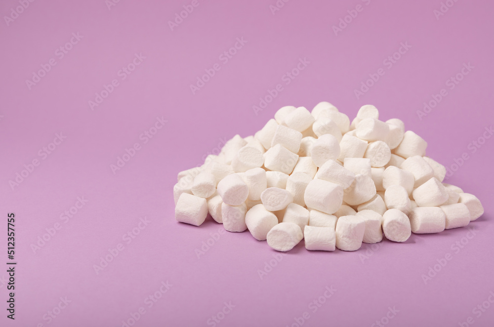 Loose marshmallows on a lilac background. White marshmallow flat lay. Sweets and snacks for a snack. Chewing candies close-up. Copy space. Place for text. Winter food concept. Loose marshmallows on a lilac background. White marshmallow flat lay. Sweets and snacks for a snack. Chewing candies close-up. Copy space. Place for text. Winter food concept.