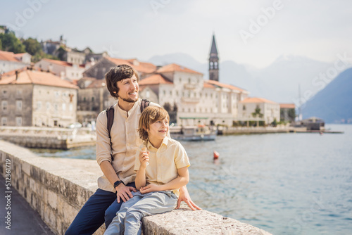 Dad and son tourists enjoying Colorful street in Old town of Perast on a sunny day, Montenegro. Travel to Montenegro concept. Scenic panorama view of the historic town of Perast at famous Bay of Kotor