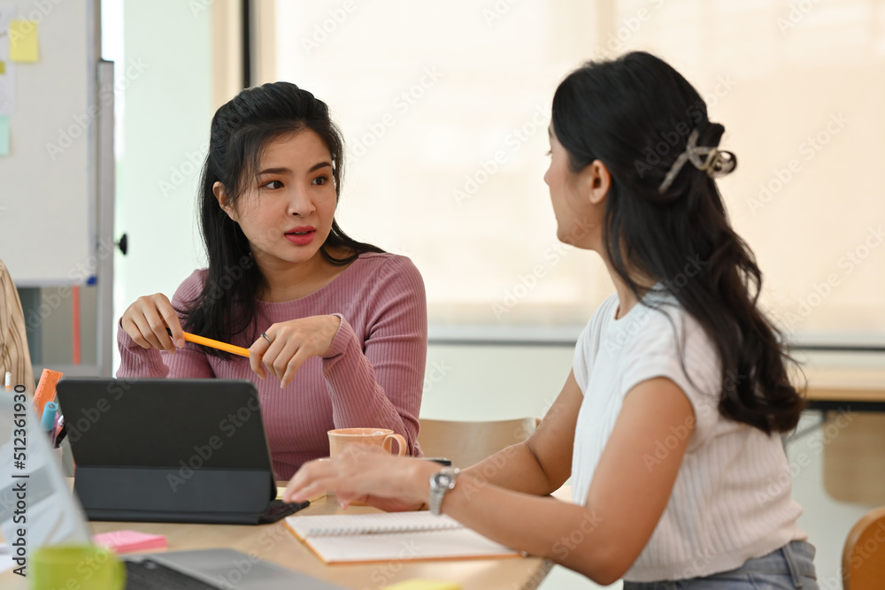 A portrait of beautiful Asian businesspeople sitting in an office, working together on a tablet and having a conversation, for business and technology concept. A portrait of beautiful Asian businesspeople sitting in an office, working together on a tablet and having a conversation, for business and technology concept.