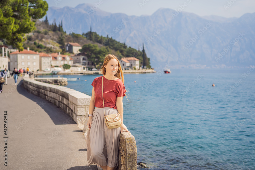 Woman tourist enjoying Colorful street in Old town of Perast on a sunny day, Montenegro. Travel to Montenegro concept. Scenic panorama view of the historic town of Perast at famous Bay of Kotor on a