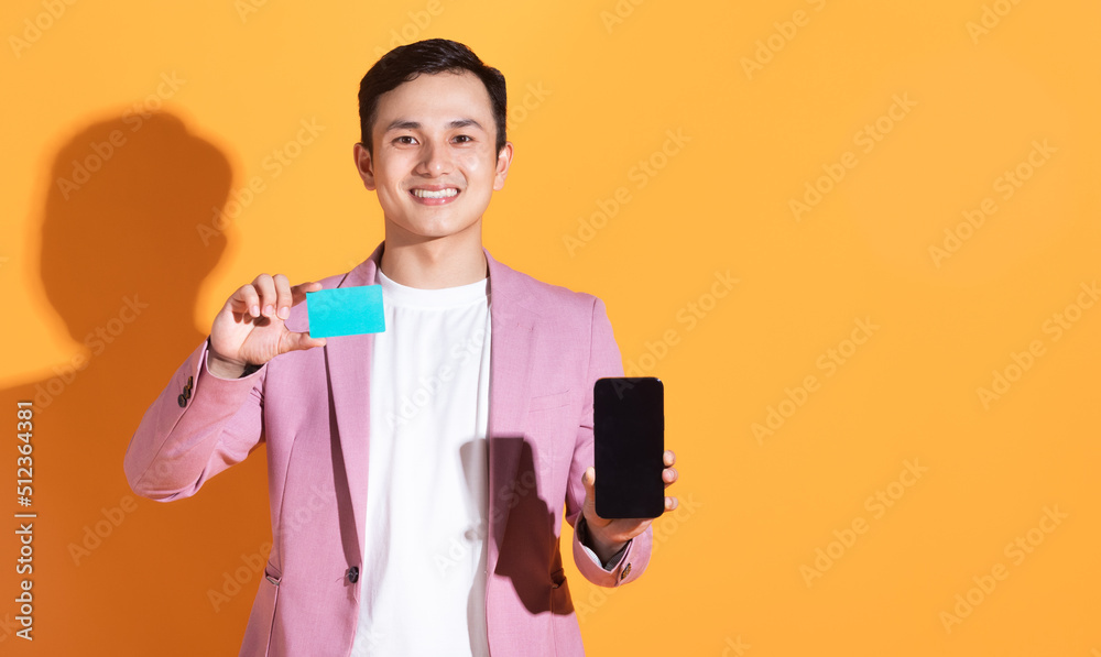 Image of young Asian man holding bank card, atm card on background Image of young Asian man holding bank card, atm card on background