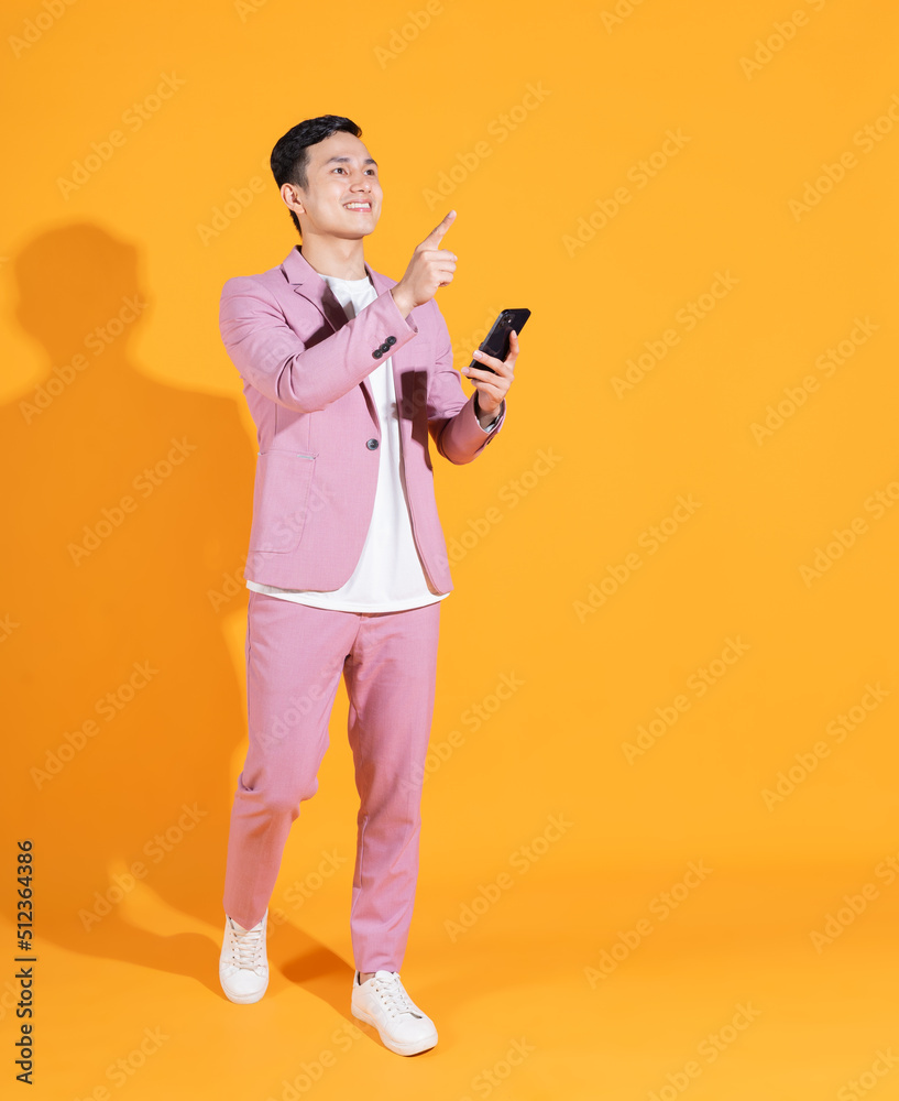 Full length image of young Asian man standing on orange background Full length image of young Asian man standing on orange background