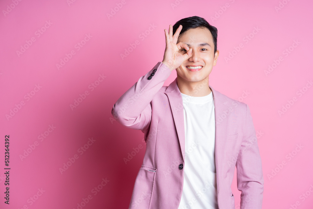 Portrait of young Asian man wearing pink suit posing on background Portrait of young Asian man wearing pink suit posing on background
