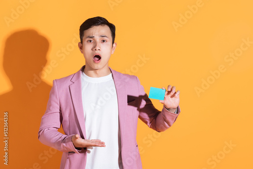 Image of young Asian man holding bank card, atm card on background