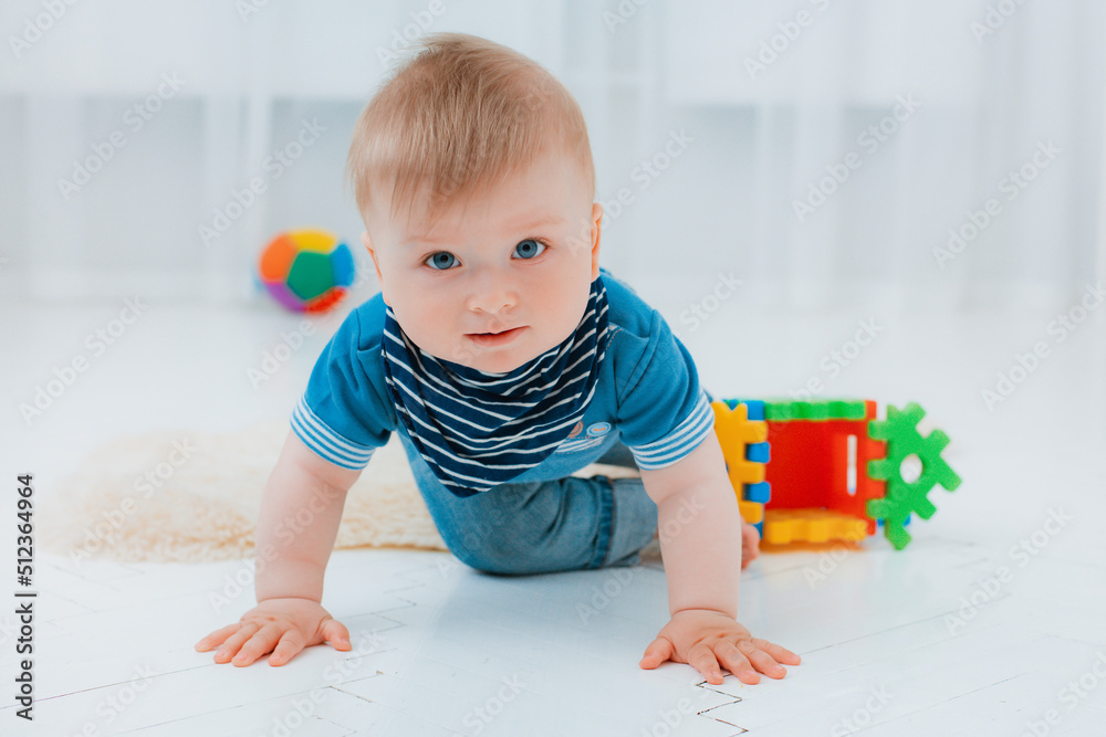 cute baby is sitting on the floor of the house, playing with colorful educational toys cute baby is sitting on the floor of the house, playing with colorful educational toys