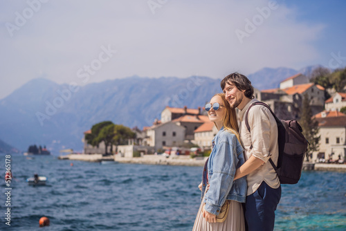 Happy couple in love man and woman tourists enjoying Colorful street in Old town of Perast on a sunny day, Montenegro. Travel to Montenegro concept. Scenic panorama view of the historic town of Perast