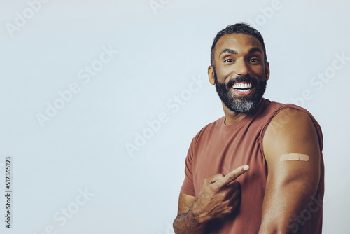 Photo portrait mid adult bearded vaccinated man looking at camera pointing at plaster