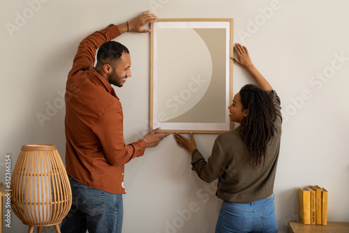 Obraz na plátně Black Husband And Wife Hanging Picture In Frame At Home