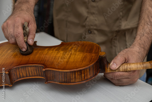 Fotografie Close-up of unrecognizable Latin American Luthier varnishes a violin the old fashioned way using natural dyes
