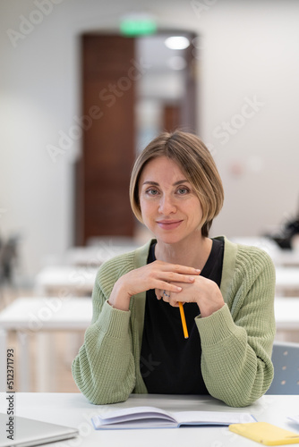 Returning to university as mature student. Happy female adult learner smiling at camera while studying in classroom, middle-aged woman getting second higher education, attending educational courses