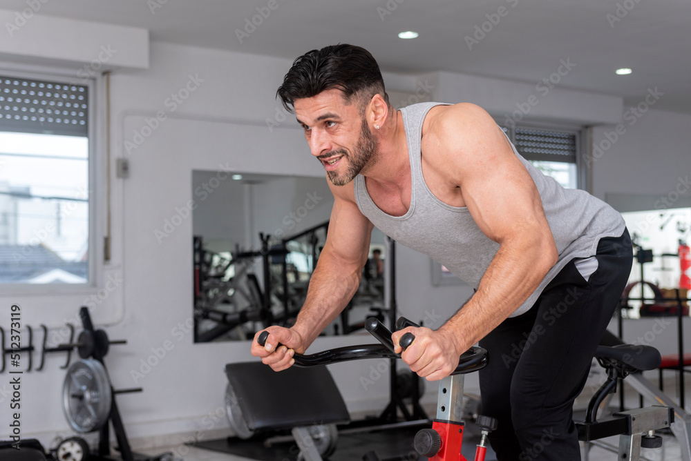 athlete man training in the gym with stationary bike doing spinning athlete man training in the gym with stationary bike doing spinning