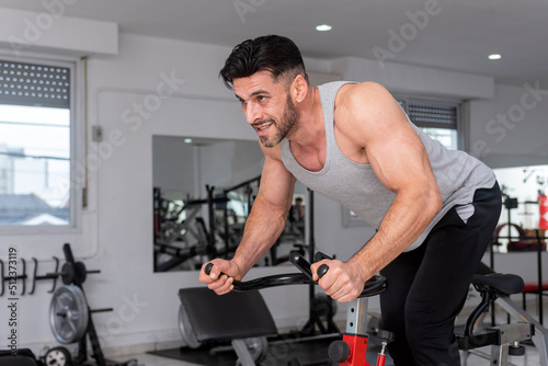 athlete man training in the gym with stationary bike doing spinning