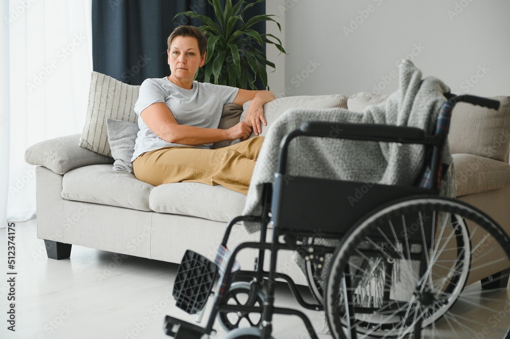 Brunette woman on couch near wheelchair Brunette woman on couch near wheelchair