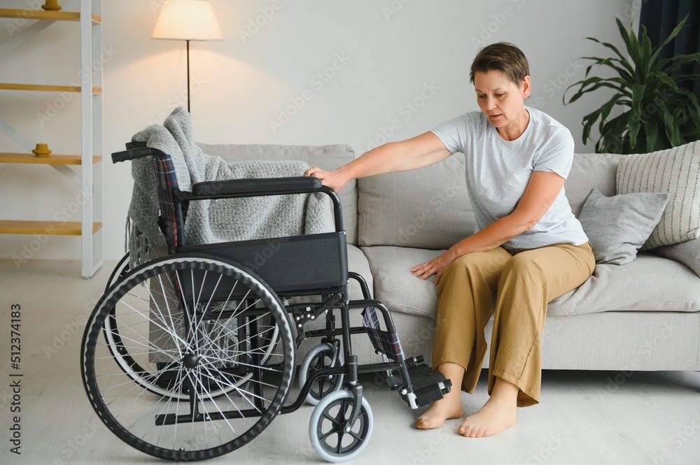 Obraz premium Senior woman trying to sit down in wheelchair from couch