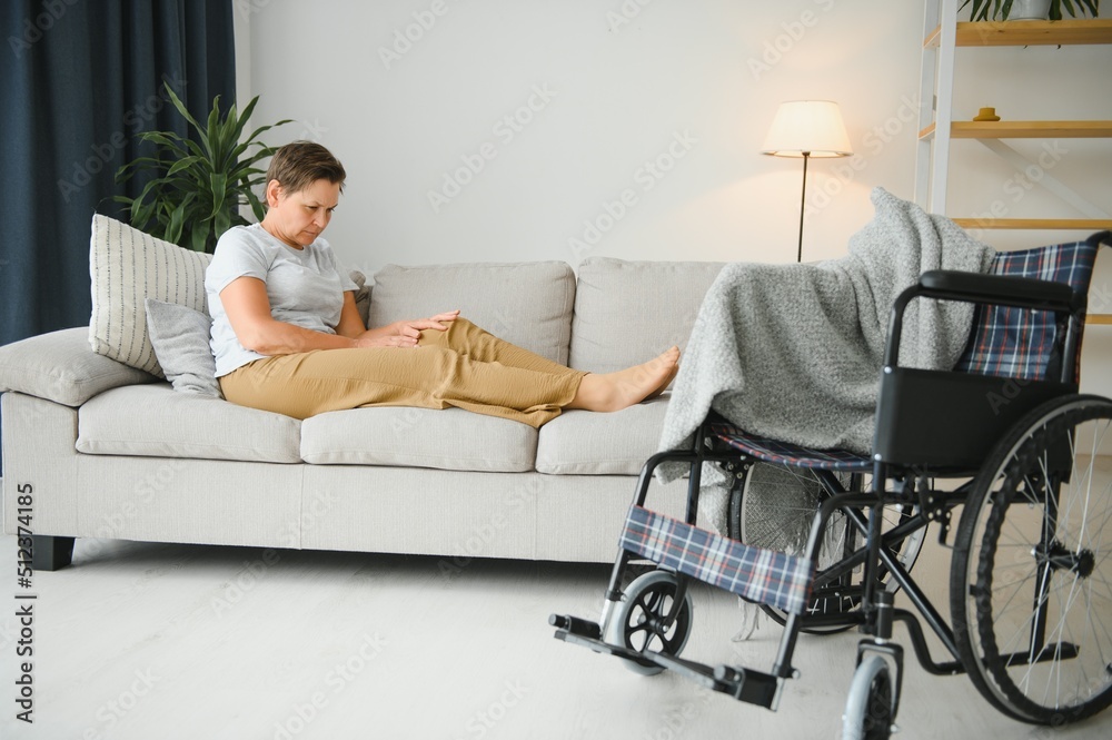 Brunette woman on couch near wheelchair Brunette woman on couch near wheelchair