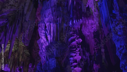 Stalactites and rock columns lit by purple light, St. Michael's cave.
