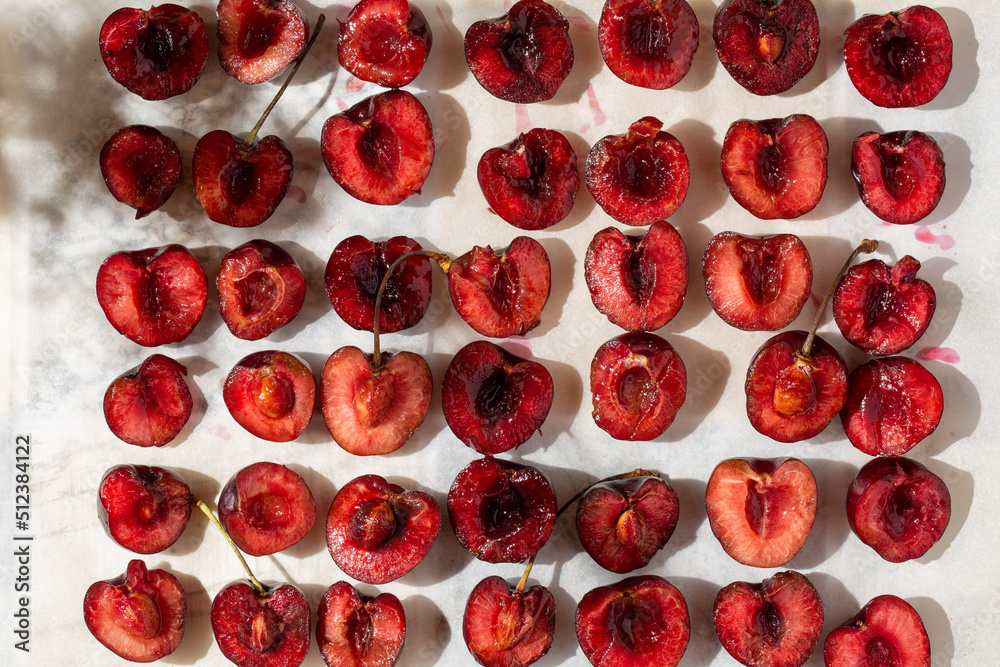 Fototapeta premium Halves of sweet cherry berries on baking sheet. Roasted Cherries. Ready for baking. Top view.