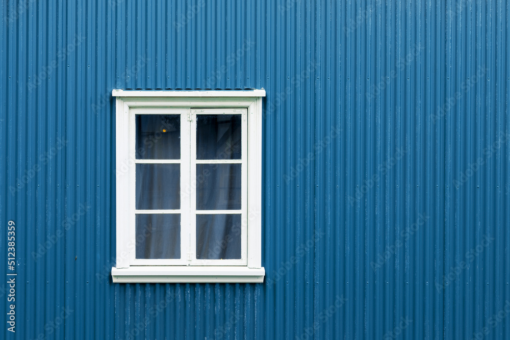 Window on a blue painted wall, colorful house, architecture detail in Reykjavik, Iceland
