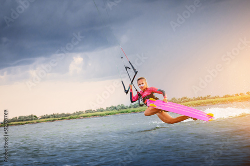 A young woman kitesurfer rides the waves doing a trick. Marine sports. kitesurfing