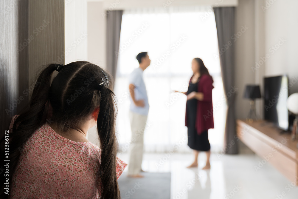 Back view of child girl crying at the door from father and mother arguing. Little girl crying because parents arguing blur background. family negative, quarrels concept. Back view of child girl crying at the door from father and mother arguing. Little girl crying because parents arguing blur background. family negative, quarrels concept.
