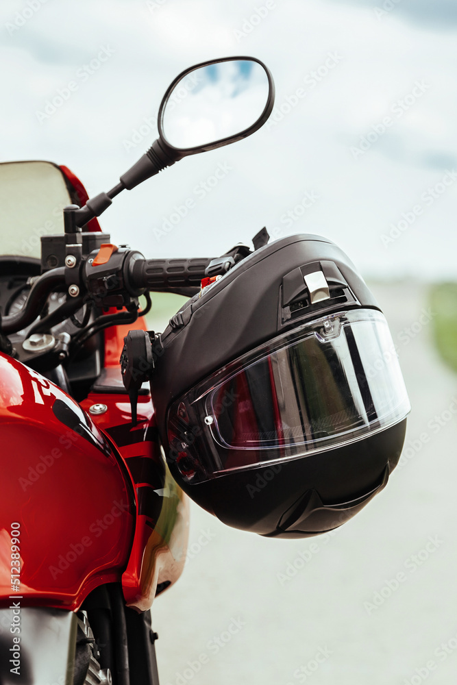 Fototapeta premium Motorcycle helmet hanging on motorcycle handle, close up