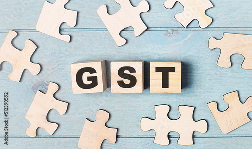 Blank puzzles and wooden cubes with the text GST Goods and Services Tax lie on a light blue background.