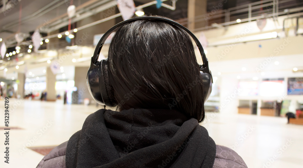 woman from the back, with black headphones