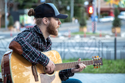 Male street musician plays the acoustic guitar.