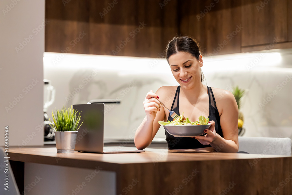 Beautiful woman eating vegetable salad in kitchen Beautiful woman eating vegetable salad in kitchen