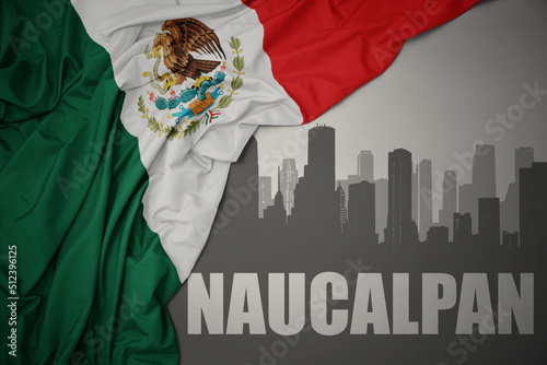 abstract silhouette of the city with text Naucalpan near waving colorful national flag of mexico on a gray background. photo