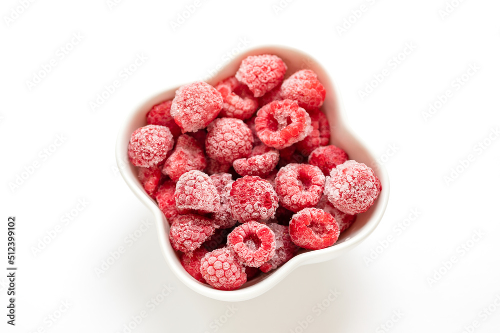 Frozen organic raspberry in white bowl on white background. View from above.