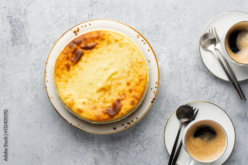 Breakfast concept. Top view of acottage cheese casserole with cups of coffee on a concrete light gray background. Coffee break with cheesecake.