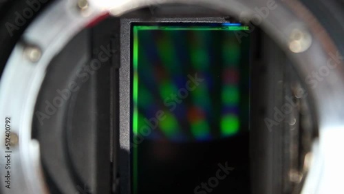 The mirror of a black DSLR camera flips up to reveal a green full frame sensor. Static vertical close up shot photo