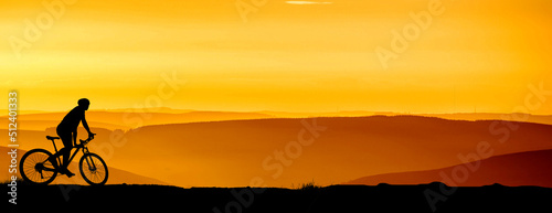 Silhouette of a mountain biker enjoying downhill during the sunset. Mountain bike concept. Mountain bike race - silhouette cyclist on background.