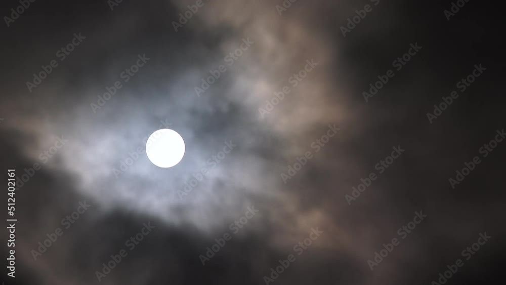 Real time clouds passing the night sky with full shining moon glowing bright.