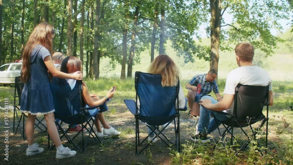 happy company, mom, dad, son, daughter and their friends are having a picnic in the forest area. family camping in summer.resting with tent in forest city park. happy company, mom, dad, son, daughter and their friends are having a picnic in the forest area. family camping in summer.resting with tent in forest city park.