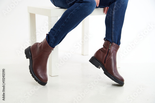 Female winter, autumn or spring brown leather shoes on leg of woman in studio on white background. Fashionable modern photography and photoshoot for a store, catalog, magazine or online