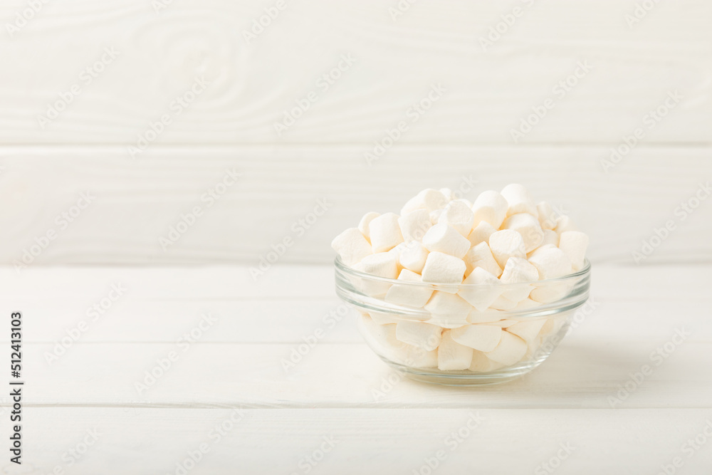 Marshmallow in a glass bowl on a white textured background.Closeup chewy candy.Snacks and snacks for parties.Spice for coffee and cocoa.Winter food concept.Place for text.Space for copy. Marshmallow in a glass bowl on a white textured background.Closeup chewy candy.Snacks and snacks for parties.Spice for coffee and cocoa.Winter food concept.Place for text.Space for copy.