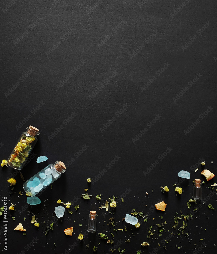 Dry tea and sugar crystals in glass bottles on a dark background Dry tea and sugar crystals in glass bottles on a dark background