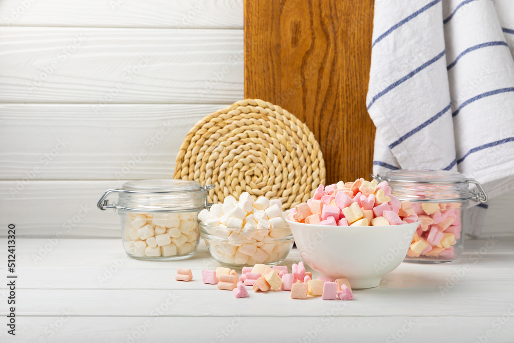 Many different marshmallows in bowls and jars on a white textured wood.  White and fruit marshmallow. Sweets and snacks for a snack. Chewing candies  close-up. Copy space. Place for text. Photos