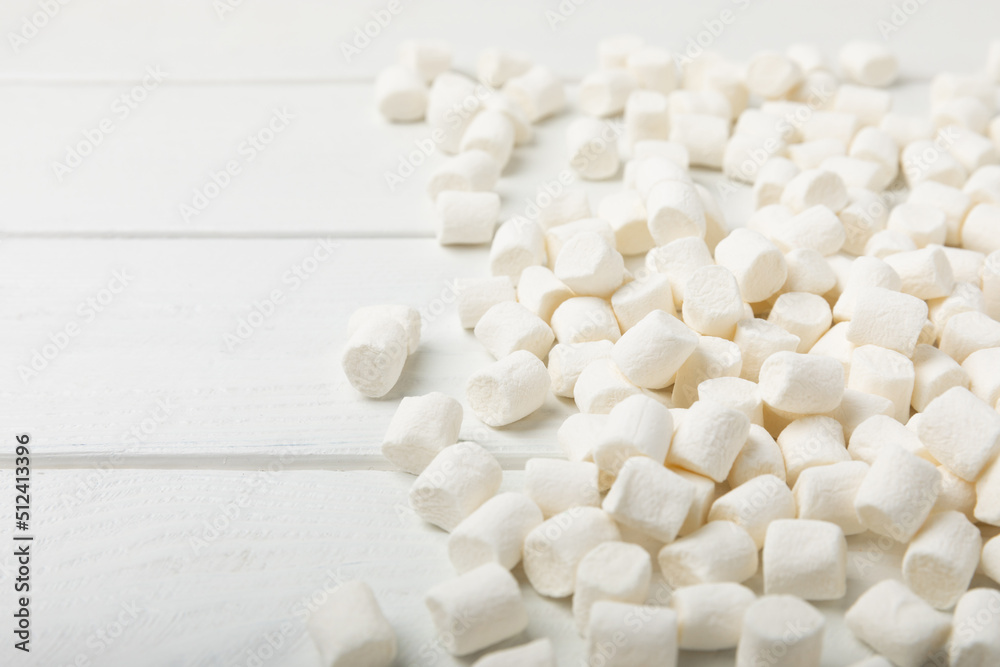 Loose white marshmallows on white texture wood.Sweets and snacks for a snack.Chewy candy close-up.Copy space.Place for text.