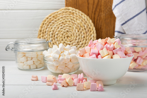 Many different marshmallows in bowls and jars on a white textured wood. White and fruit marshmallow. Sweets and snacks for a snack. Chewing candies close-up. Copy space. Place for text.