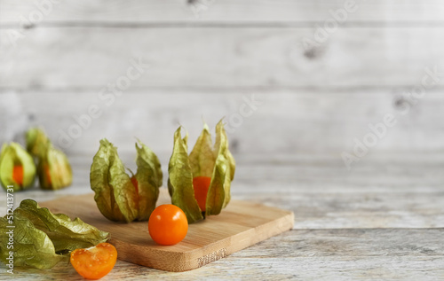Ripe healthy physalis (orange golden, gooseberry), over wooden board on a wooden background, copy space