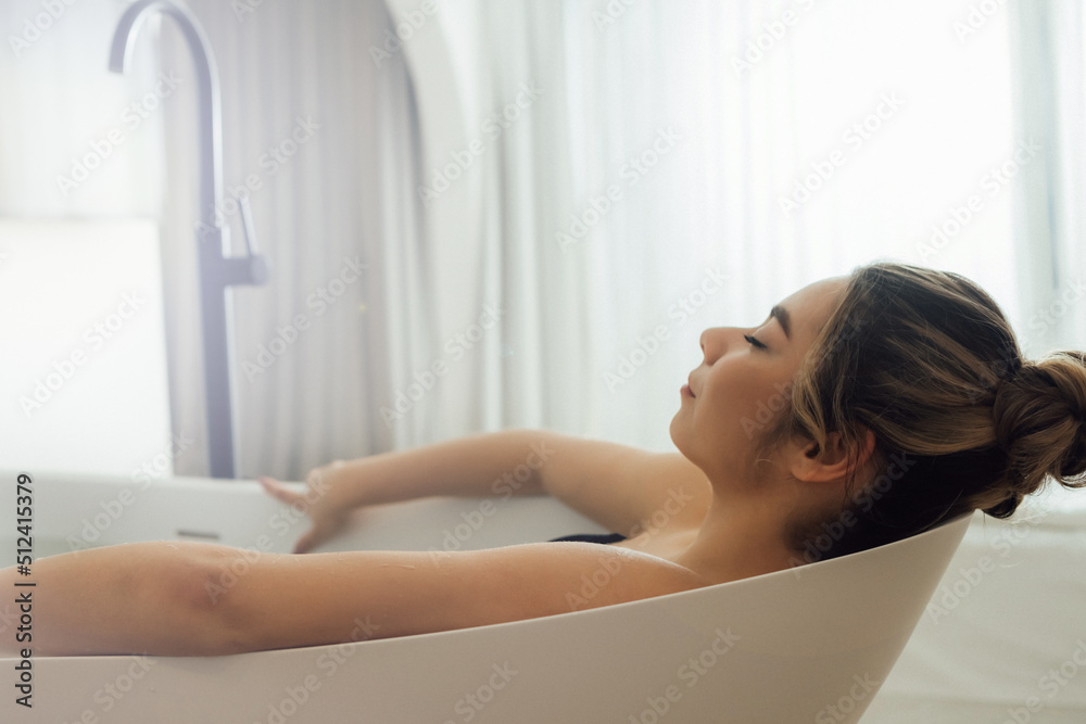 Woman in bath. Relaxed girl thinking about good moments in bathtub in white bathroom interior. Self care, hygiene and spa concept Woman in bath. Relaxed girl thinking about good moments in bathtub in white bathroom interior. Self care, hygiene and spa concept