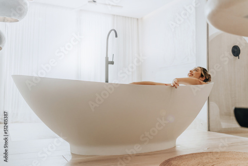 Full length view of happy pretty woman with attractive smile relaxing while taking bath in bright apartment during romantic atmosphere
