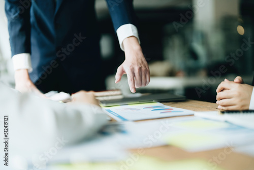 Male businessman pointing to documents summarizing marketing strategy with female colleagues in meeting, teamwork, investment planning