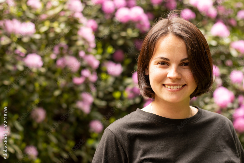 Portrait of a beautiful smiling woman in a black T-shirt against the background of a flowering bush Portrait of a beautiful smiling woman in a black T-shirt against the background of a flowering bush