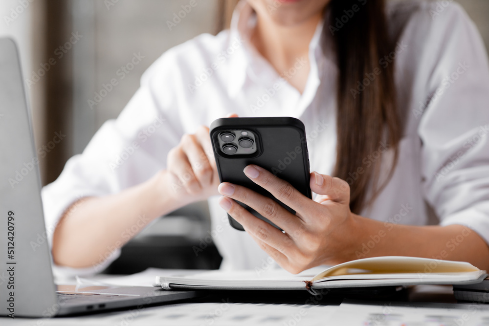 young businesswoman looking at financial information from a mobile phone, she is checking company financial documents, she is a female executive of a startup company. Concept of financial management. young businesswoman looking at financial information from a mobile phone, she is checking company financial documents, she is a female executive of a startup company. Concept of financial management.
