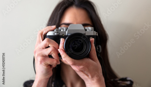 Young woman photographer hold photo camera is shoot your picture, close up close up front view
