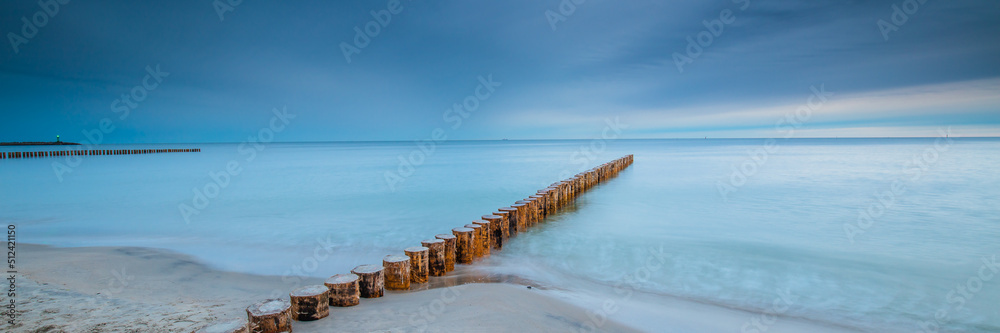 Amazing sunrise over the beach in Chalupy. Seascape with breakwater